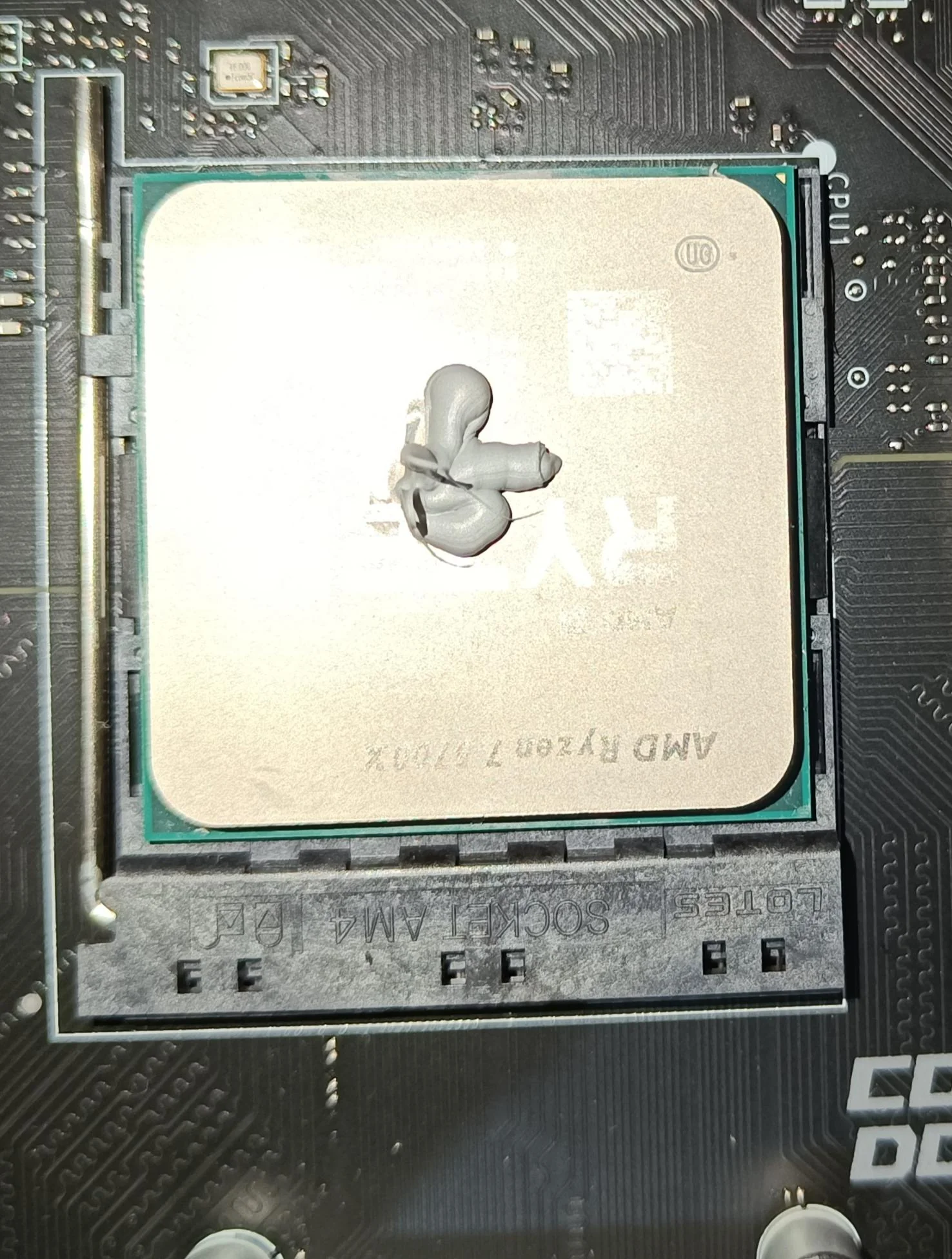 The image shows CPU (AMD Ryzen 7 5700X) with thermal paste on it